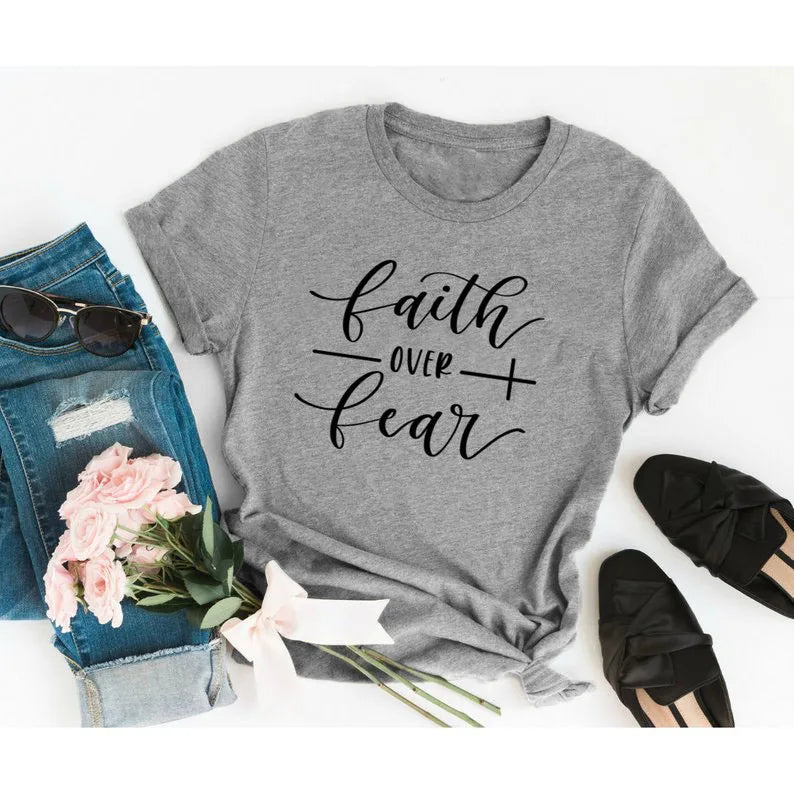 BC Faith Over Fear Christian T-Shirt in soft pink with black graphic slogan, styled with casual shoes, sunglasses, and roses for women’s fashion.