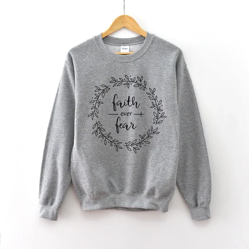 Gray women's cotton sweatshirt with black 'Faith Over Fear' wreath print. Faith Apparel's Christian-themed clothing.