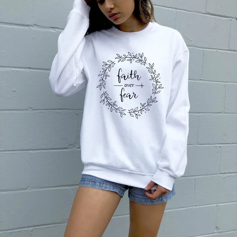 Women's cotton sweatshirt with 'Faith Over Fear' text and floral wreath design. 100% cotton Christian faith apparel in white, styled casually.