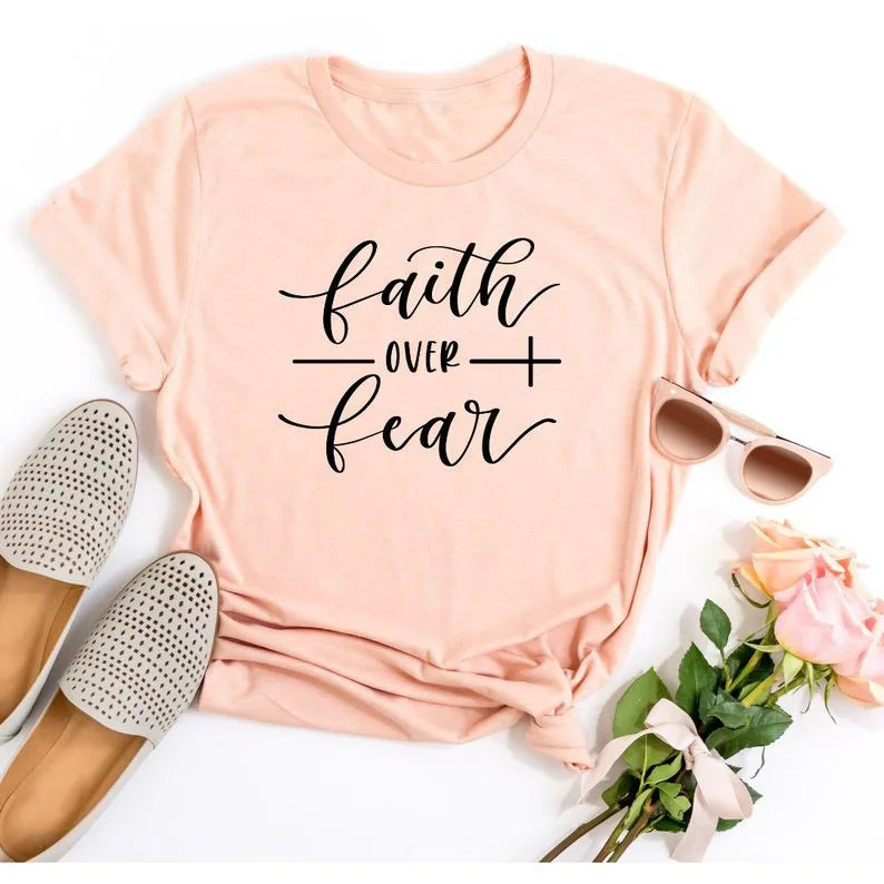 BC Faith Over Fear Christian T-Shirt in soft pink with black graphic slogan, styled with casual shoes, sunglasses, and roses for women’s fashion.